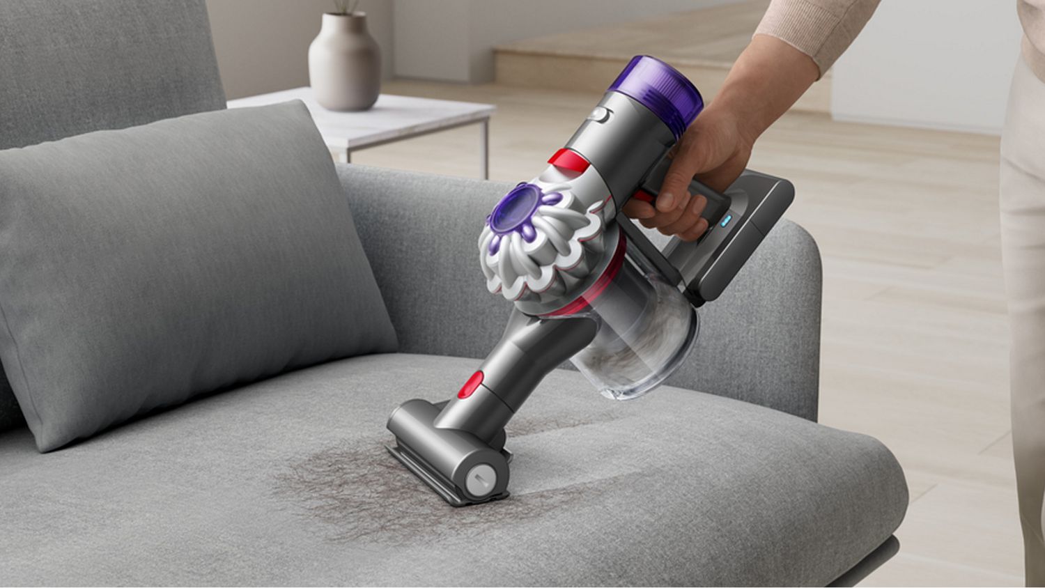 The Dyson Car+Boat handheld vacuum with the Mini motorised tool cleaning hair from a sofa.